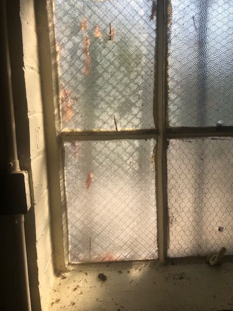 A close up of a window with a chain link fence behind it
