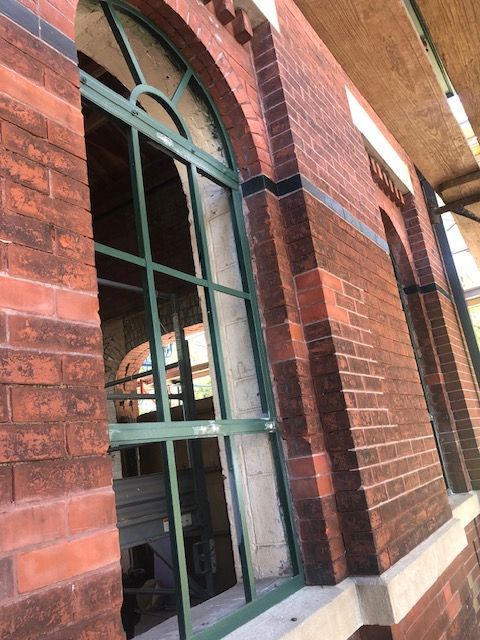 A brick building with arched windows and a green frame