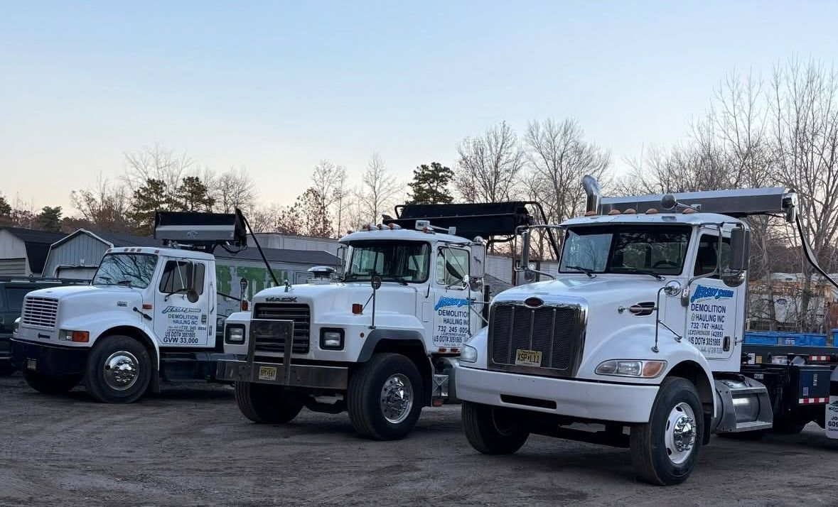 Three white tow trucks parked side by side at dusk outdoors