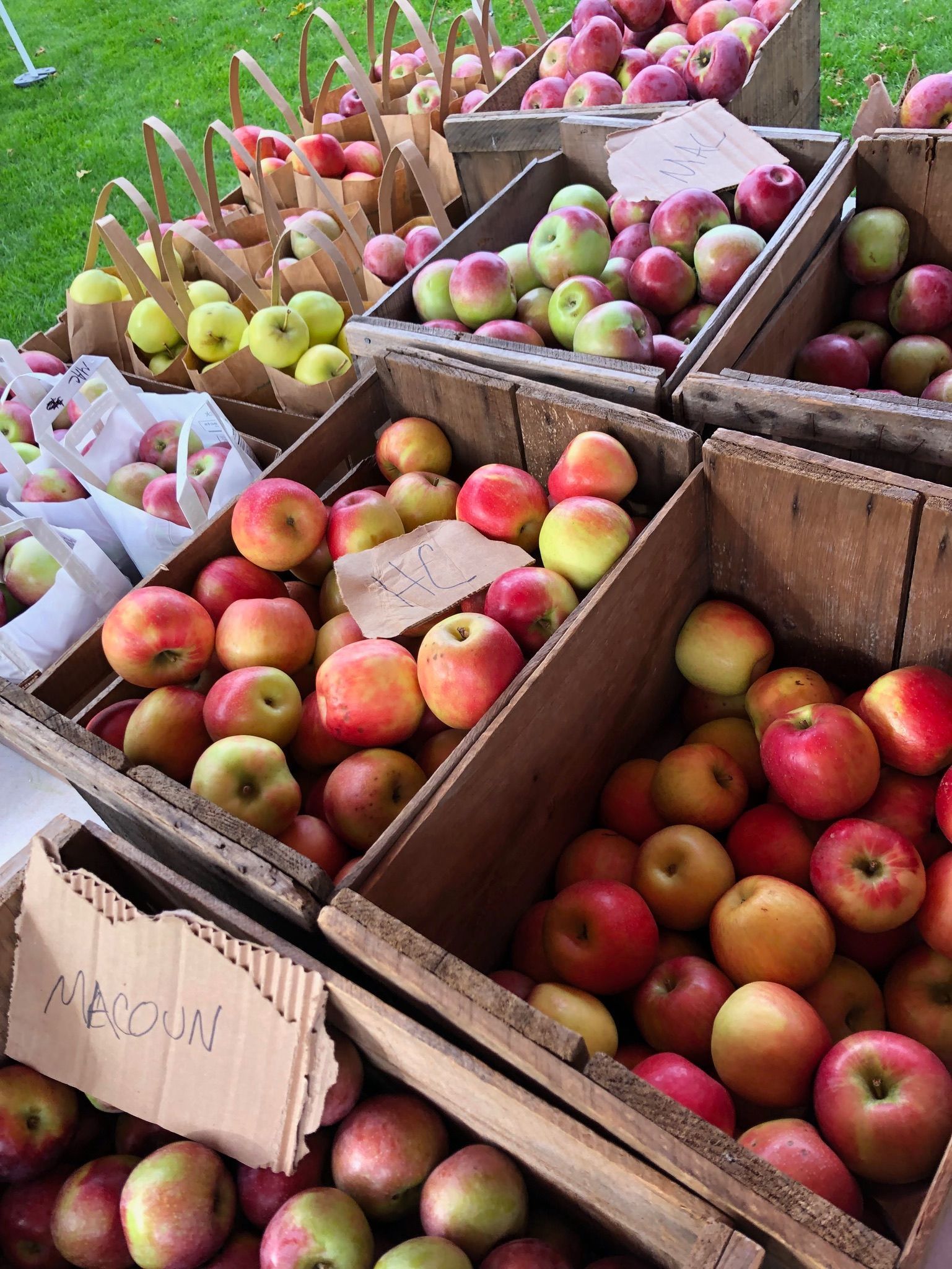 A bunch of crates of apples with one that says ' a-cola ' on it