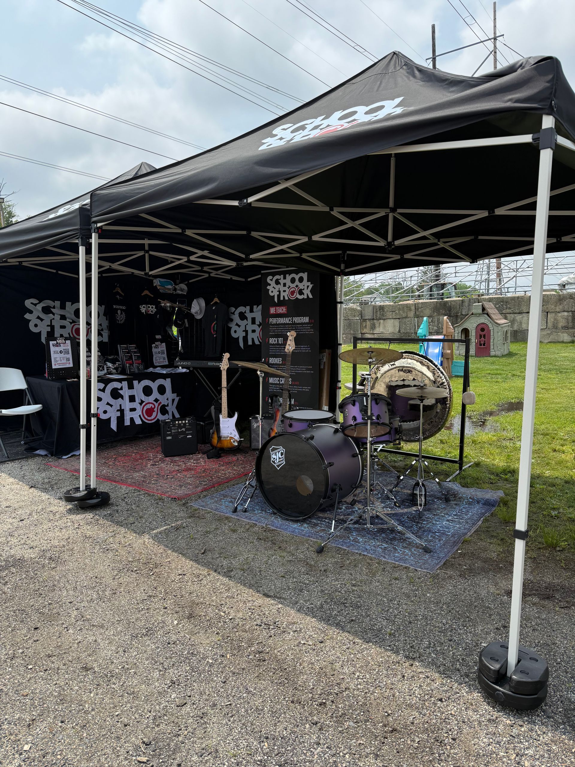 A drum set is sitting under a black tent.