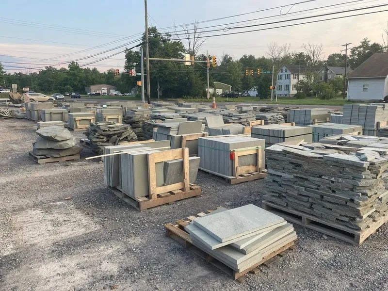 Stone pavers and slabs stacked on pallets outdoors at a building materials supplier.
