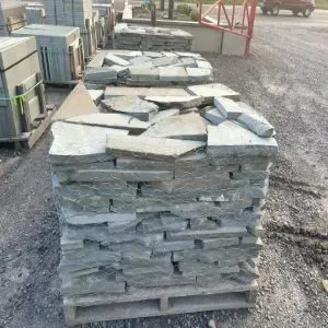 Stacked pallets of irregularly shaped gray flagstone outside.