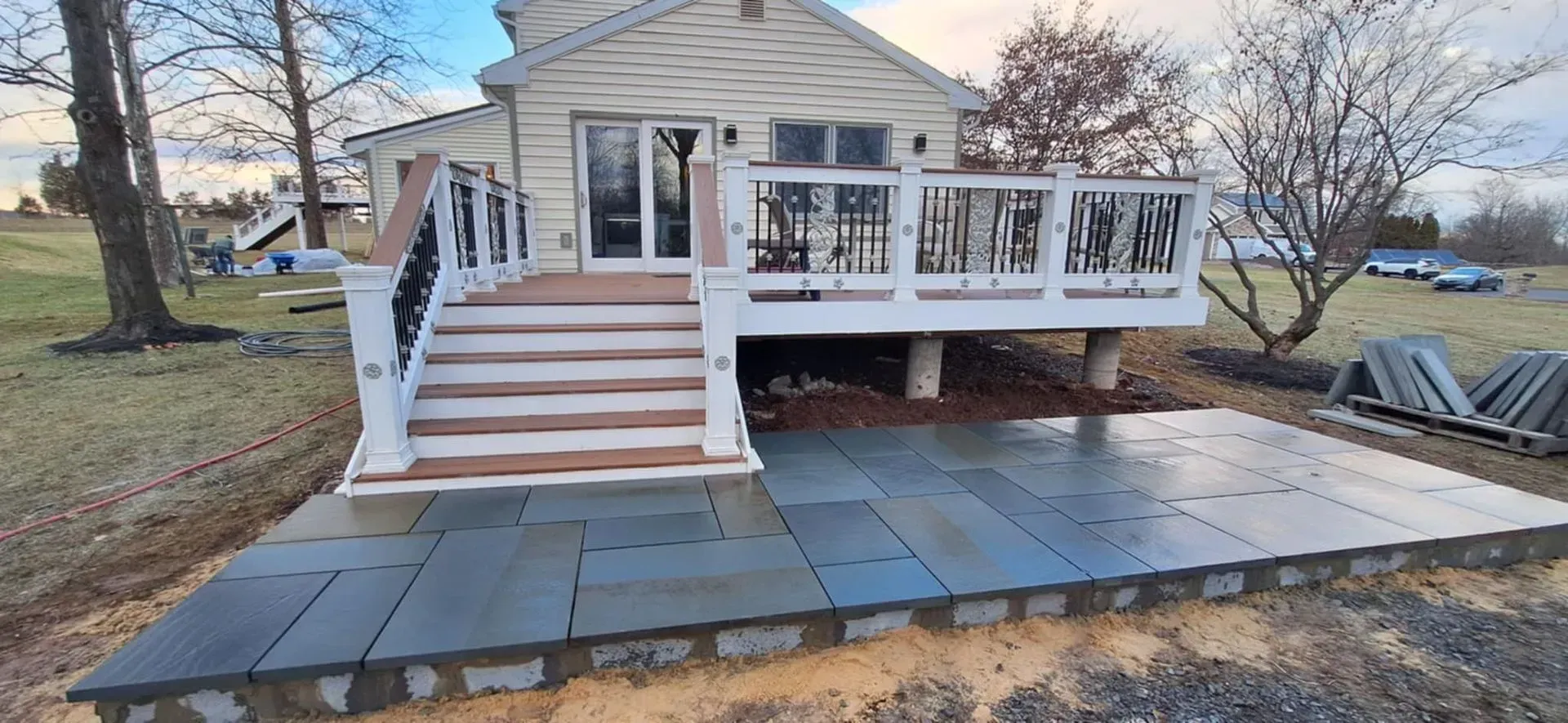 A home with a deck and patio. The patio is made of blue stone and has a raised edge. Stairs lead up to the deck.