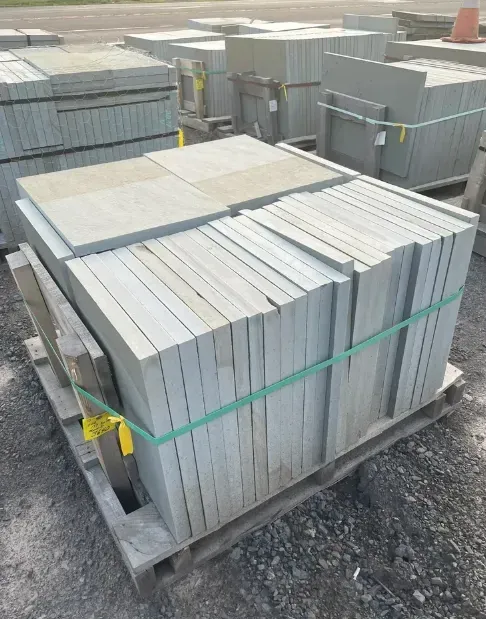 Pallet of gray stone pavers secured with green bands, likely for outdoor construction or landscaping.