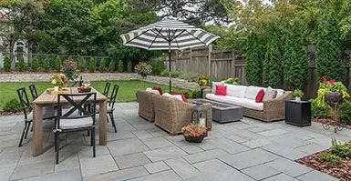 A patio with a table , chairs , couch , and umbrella.