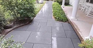 A walkway leading to a porch with rocking chairs.