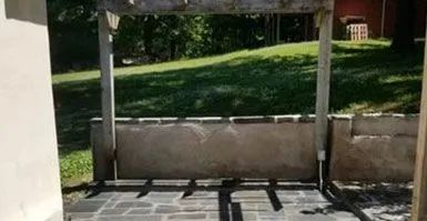 A patio with a pergola and a fence in the background.