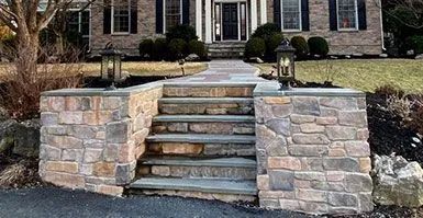 A stone walkway with stairs leading up to a brick house.
