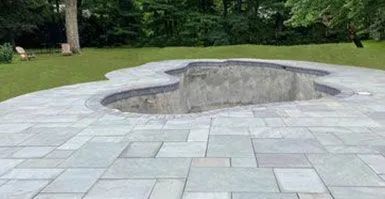 There is a hole in the ground in the middle of the patio.