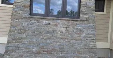 A stone wall with a window in the middle of it.