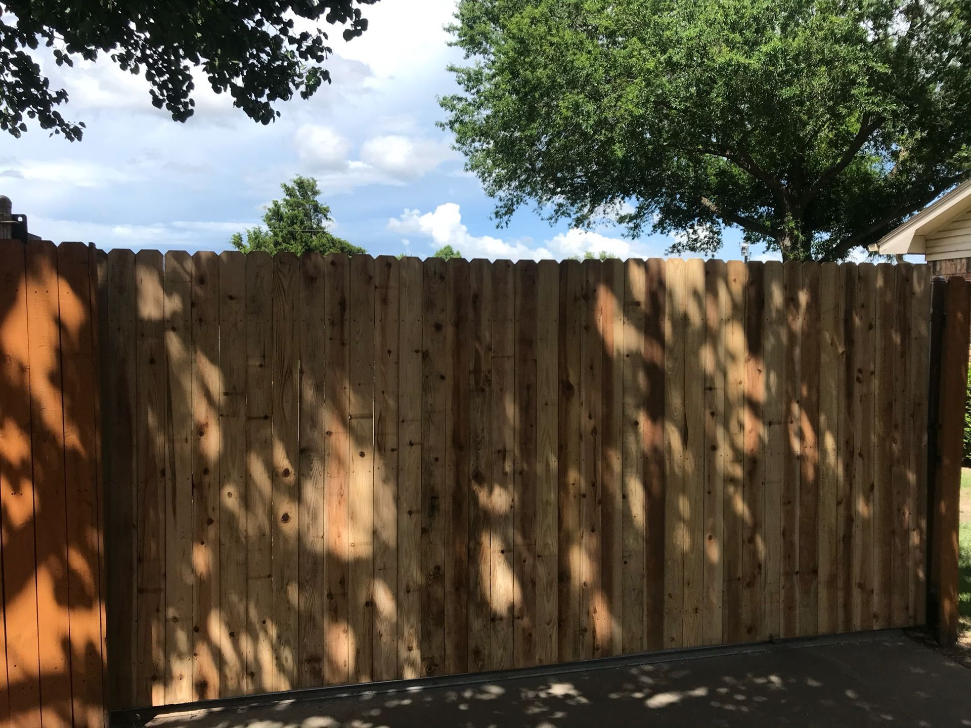 A wooden fence with trees in the background and a house in the background