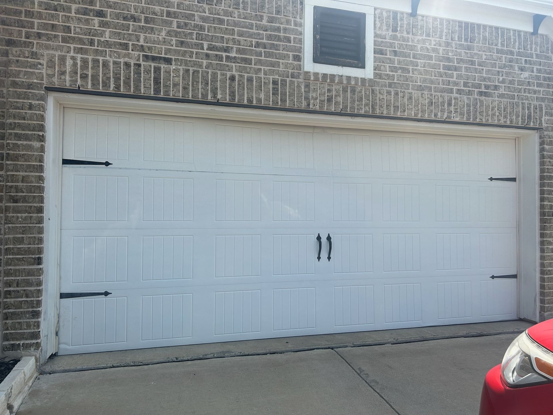 A red truck is parked in front of a white garage door
