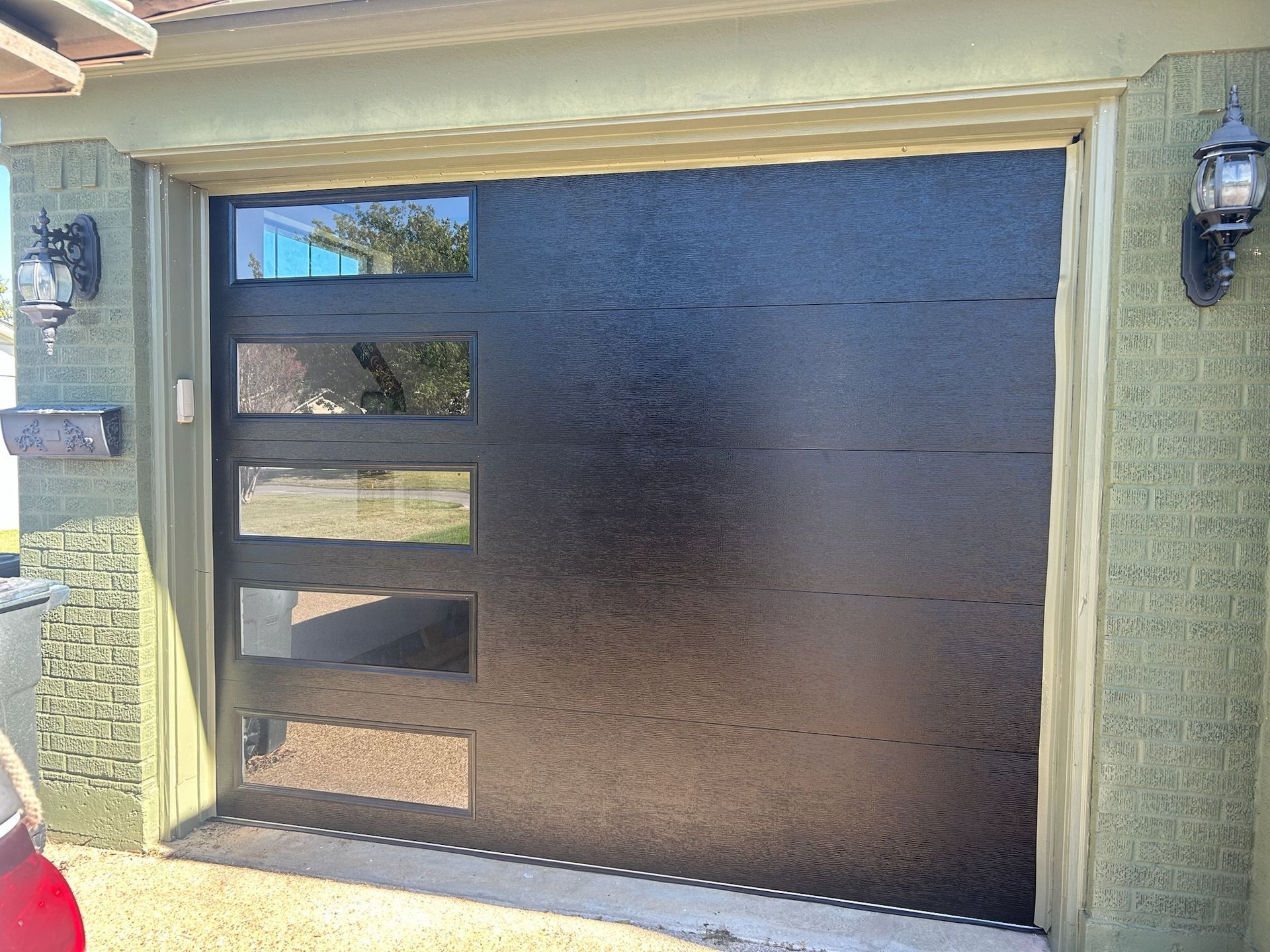 A car is parked in front of a black garage door.