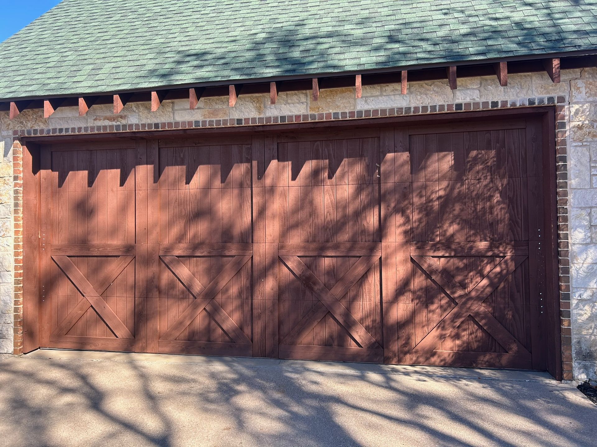 A wooden garage door with a brick wall and a green roof