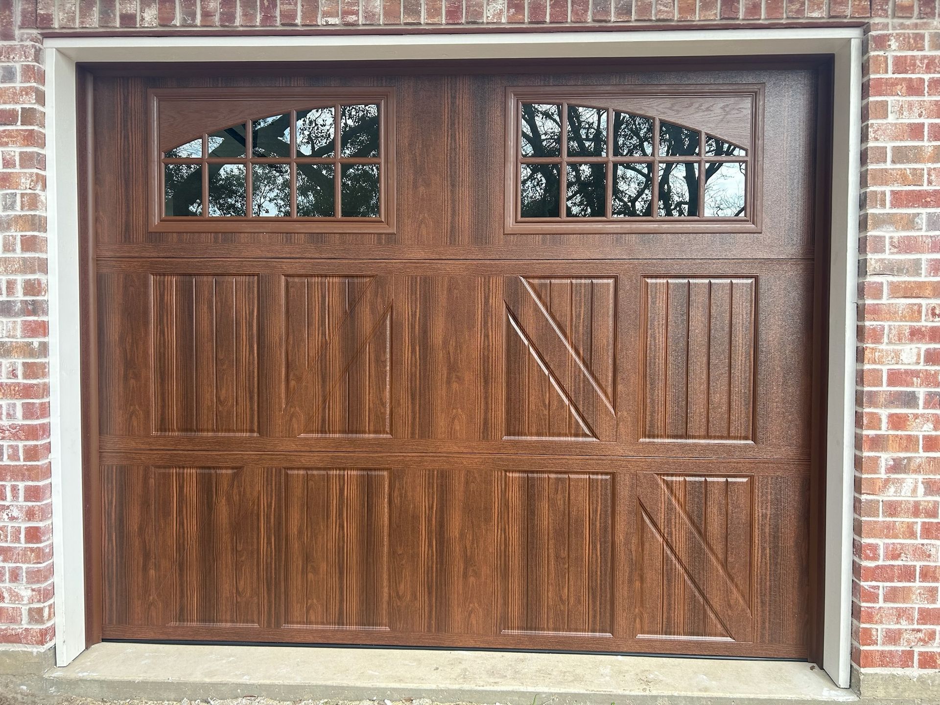 A wooden garage door with a brick wall in the background