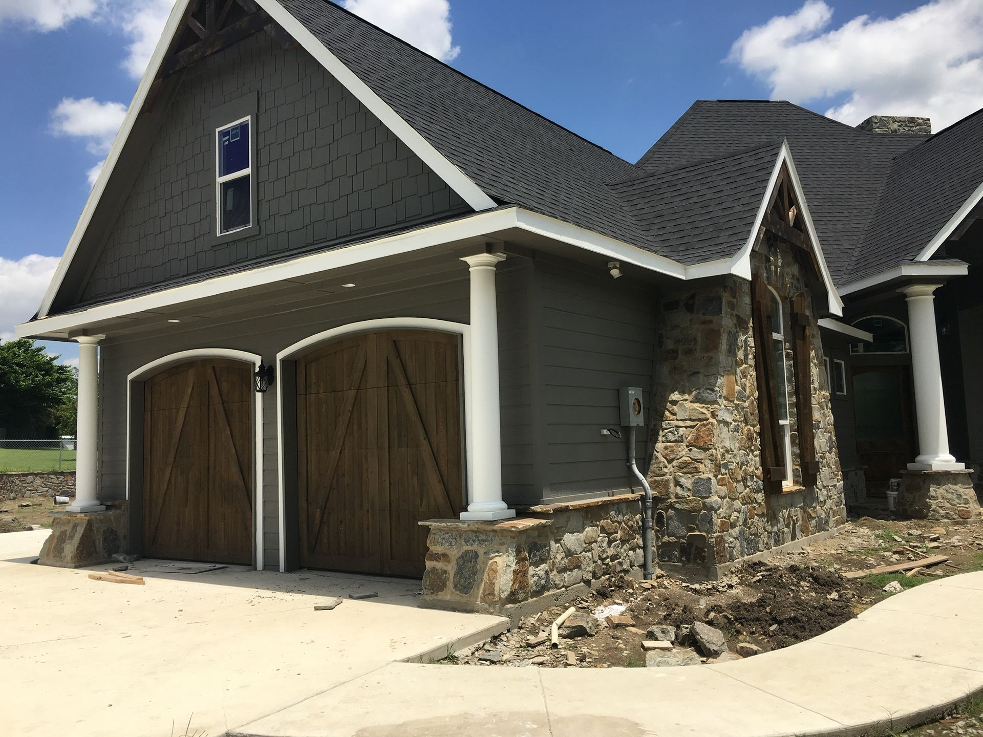 A large house with two garage doors and a walkway in front of it.