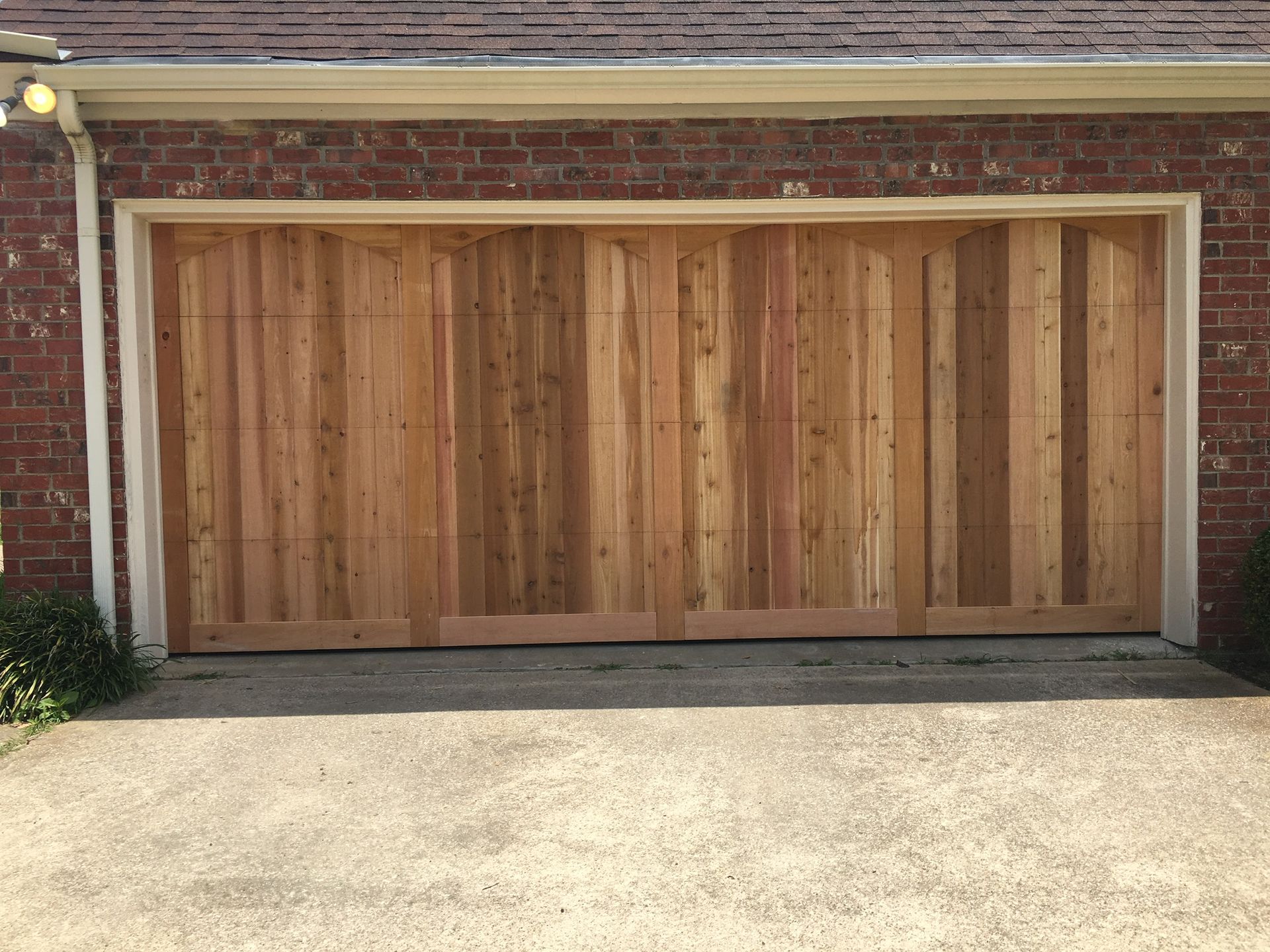 A wooden garage door is sitting in front of a brick building