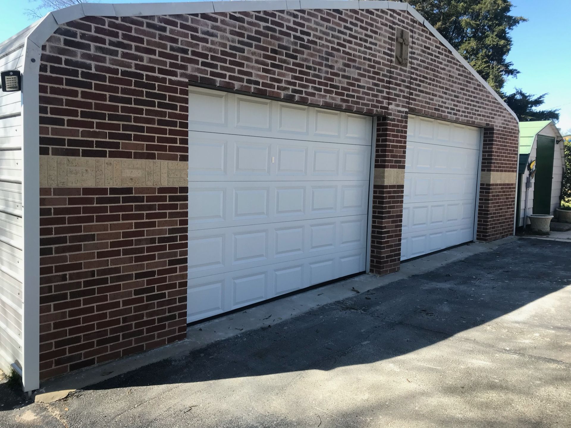 A brick garage with three white garage doors
