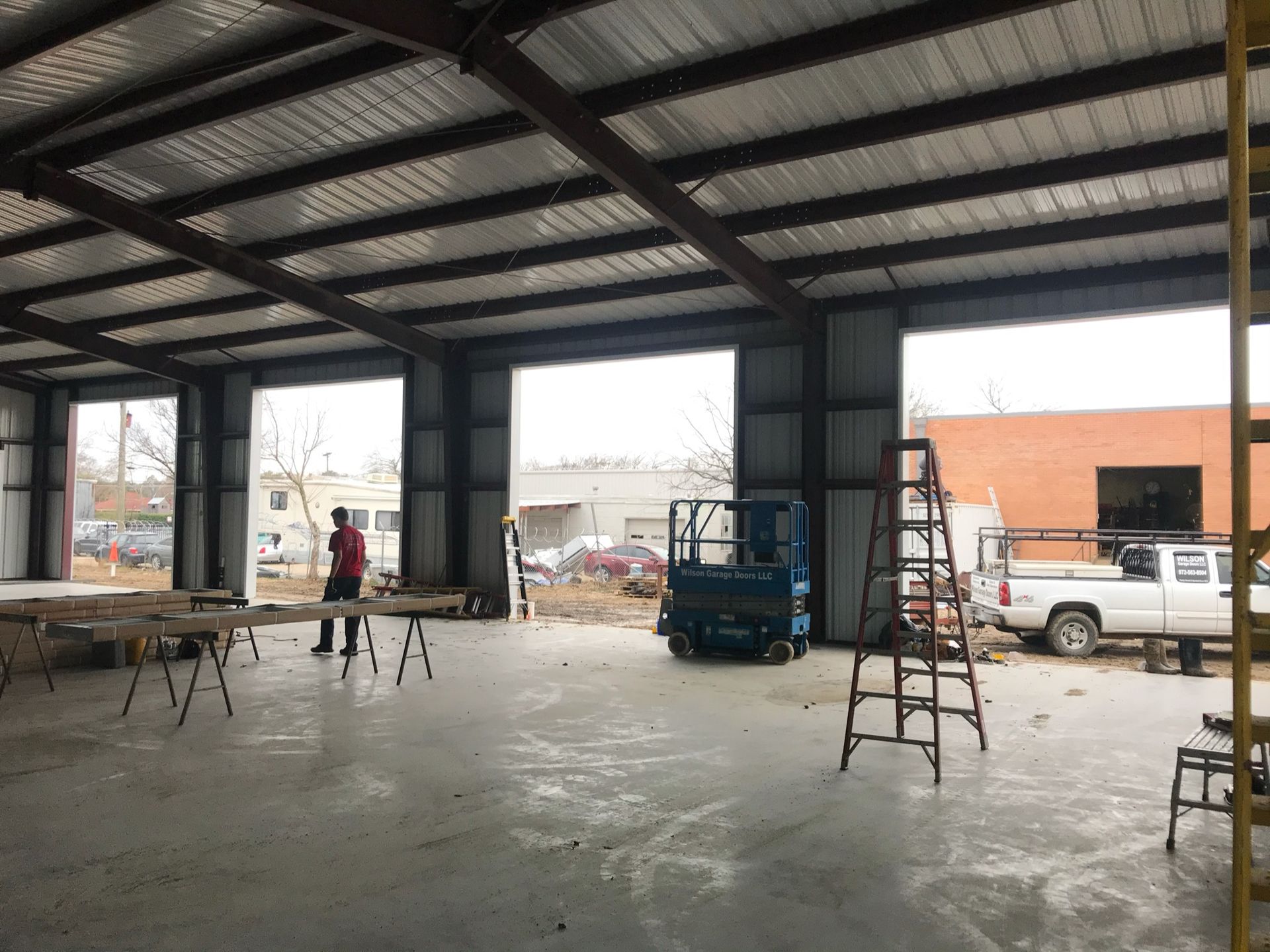 A man is standing in a large warehouse with a ladder