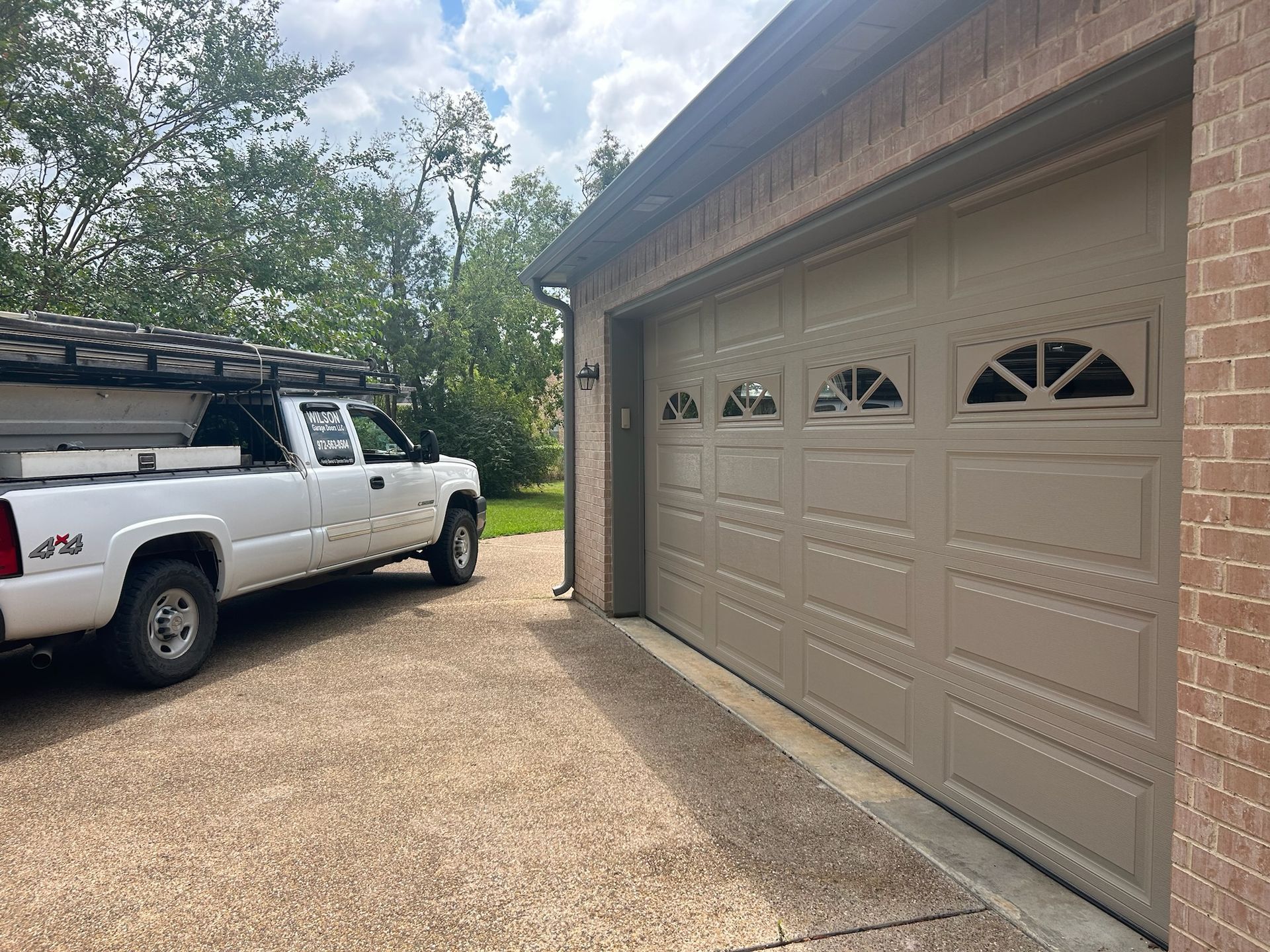 A white truck is parked in front of a garage door