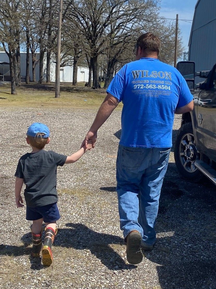 A man and a little boy are walking down a gravel road holding hands