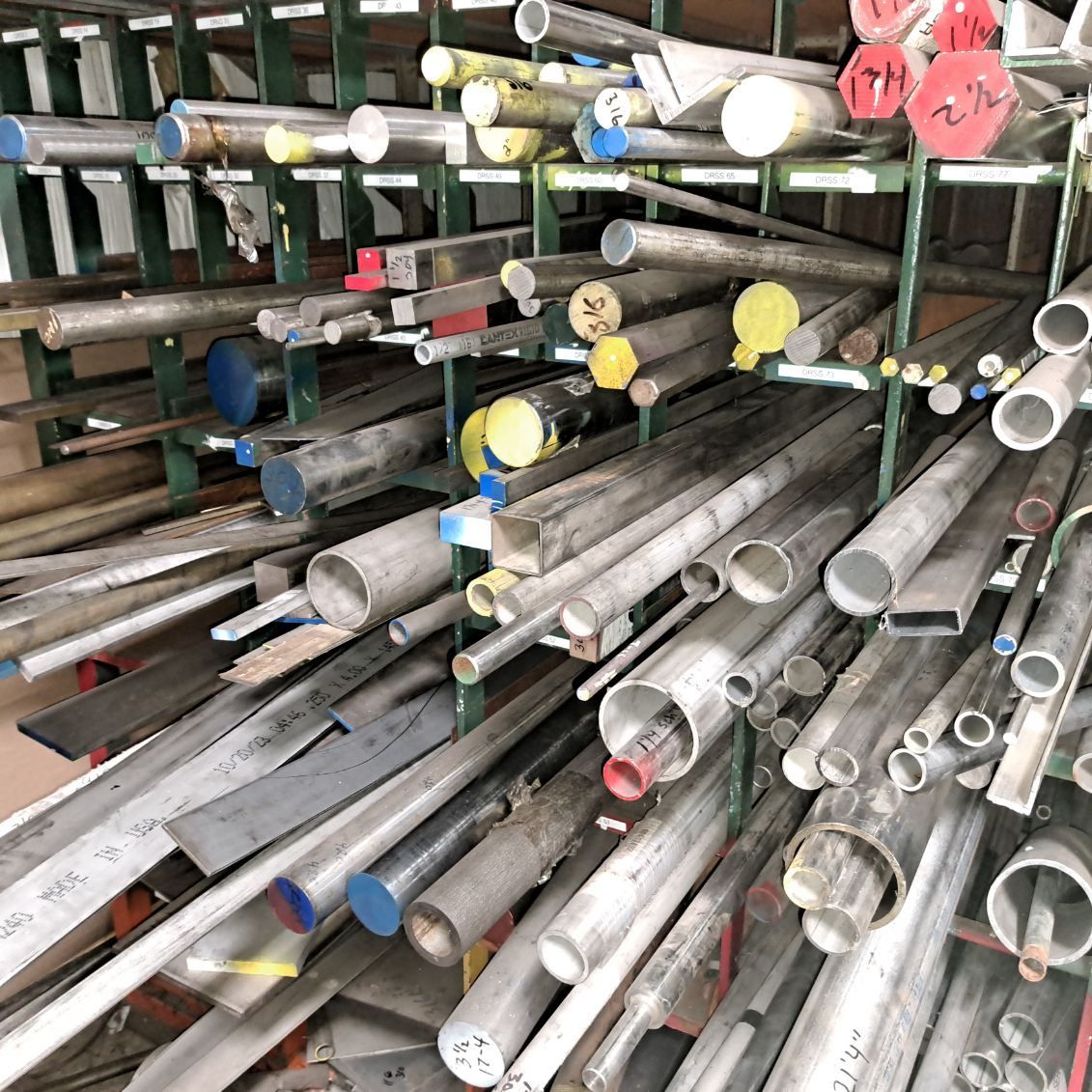 A bunch of metal pipes are stacked on top of each other in a warehouse.