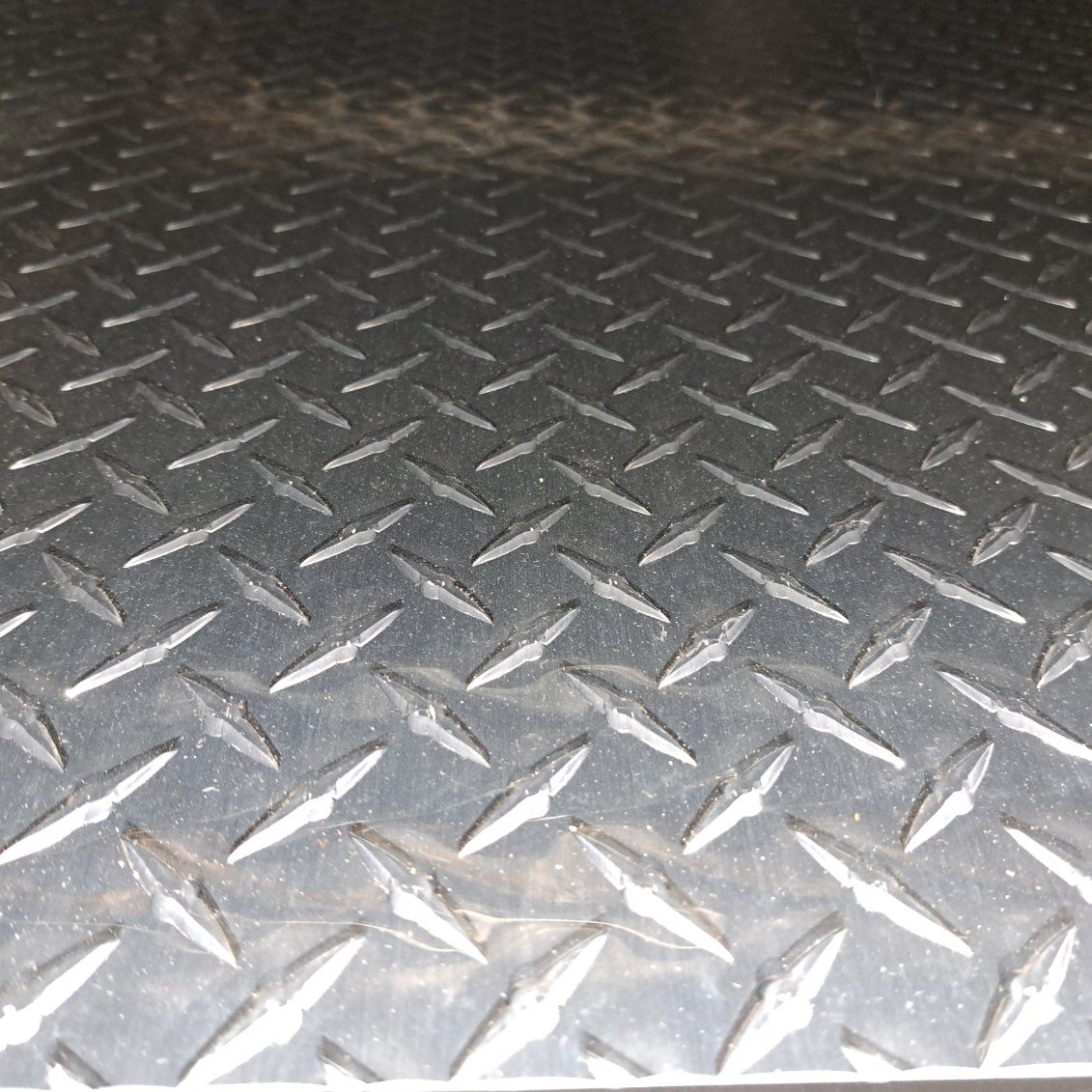 A close up of a metal surface with a diamond pattern