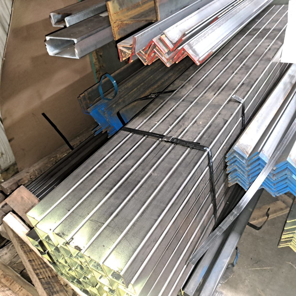 A bunch of metal bars are stacked on top of each other in a warehouse.