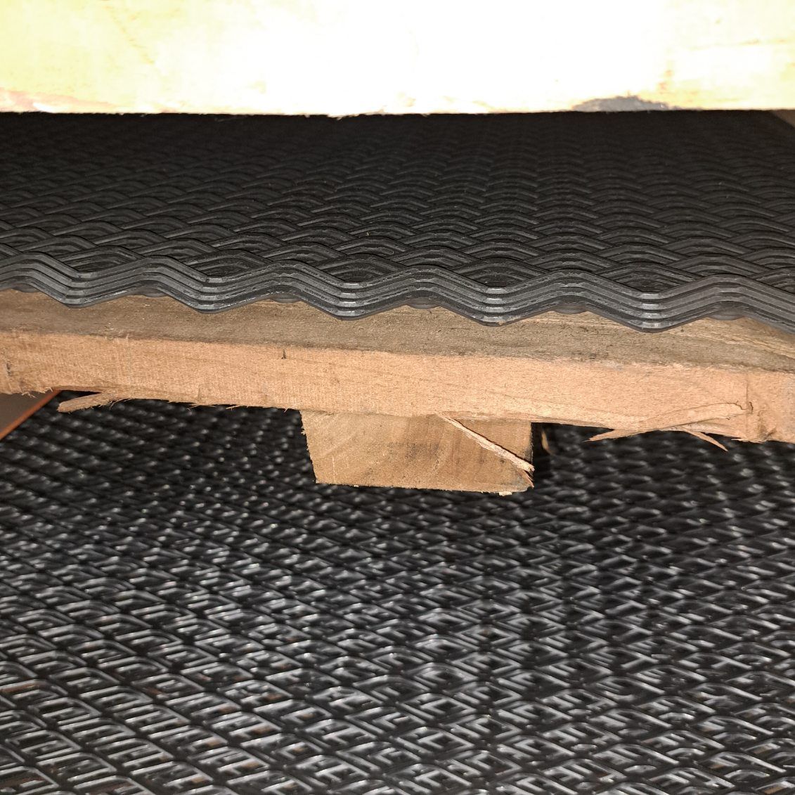 A piece of black rubber is sitting on top of a wooden pallet.