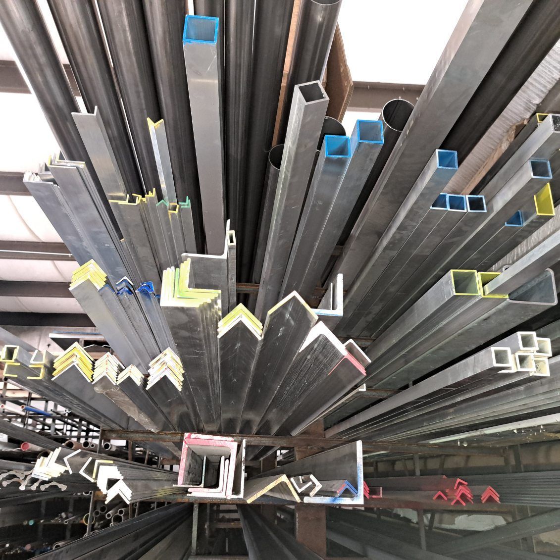 A bunch of metal pipes are stacked on top of each other in a warehouse.