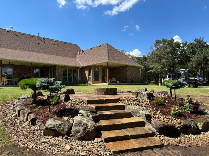 Brick house with landscaped front yard, stone steps, and blue sky