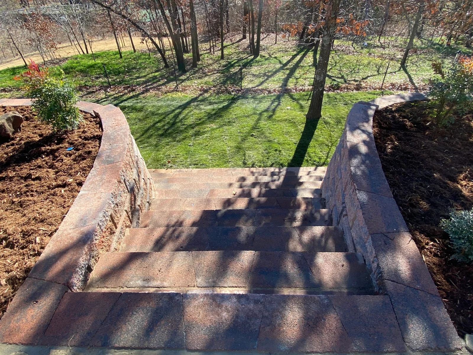 Stone steps descending to a grassy yard with trees and long shadows.