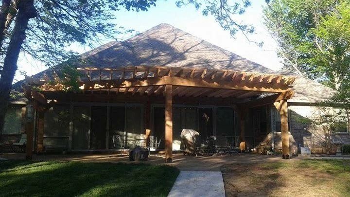 Wooden house with a shaded front porch and stone path, surrounded by trees and lawn.