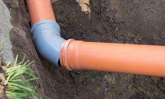 A couple of pipes are connected to each other in the dirt.