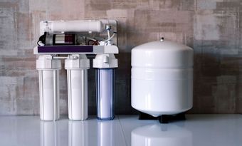 A water filter is sitting on a counter next to a tank.