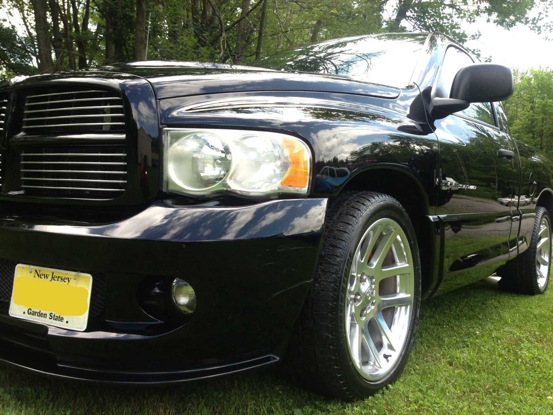 A black dodge ram is parked in the grass