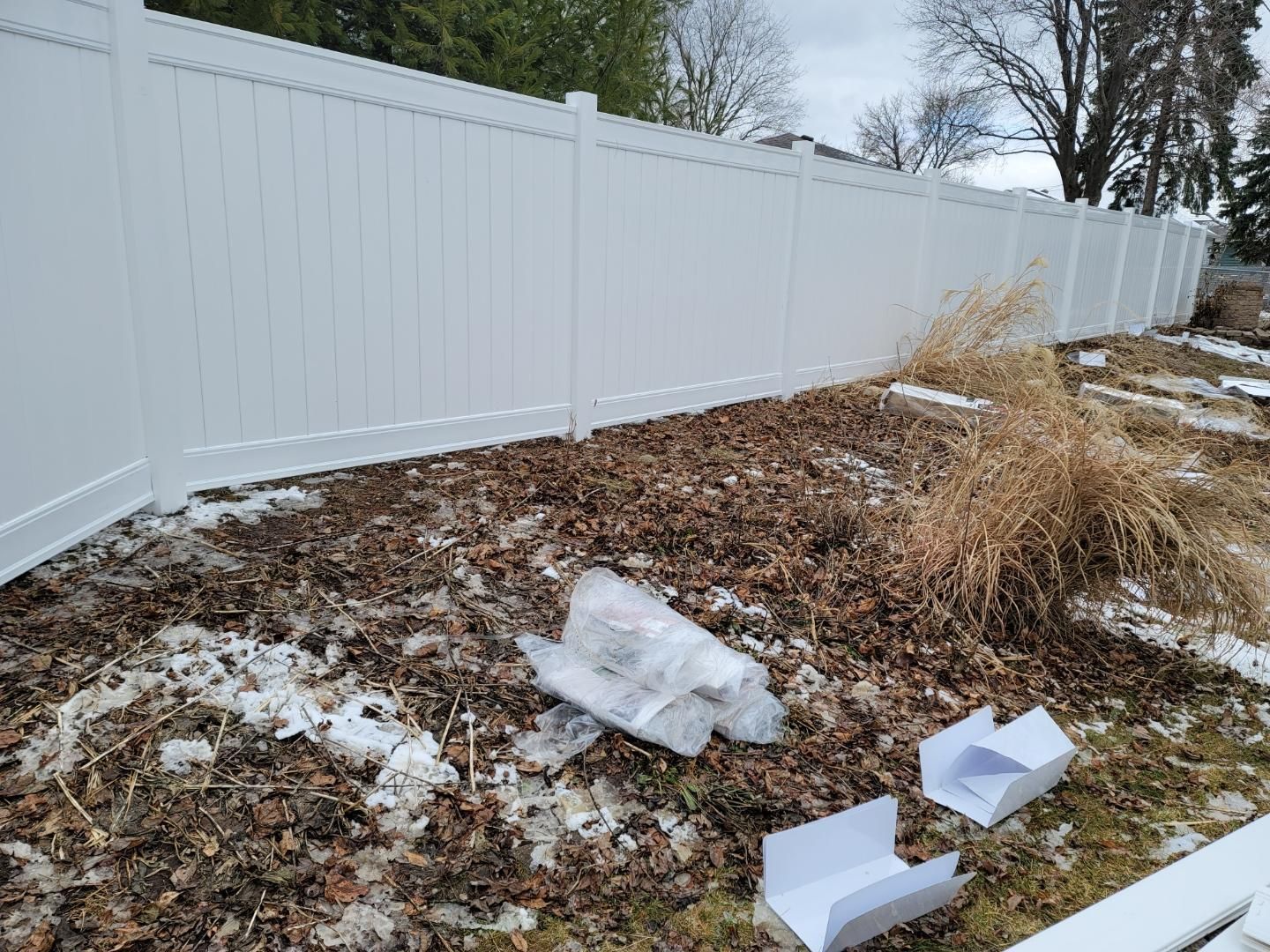 A white fence is sitting in the middle of a snowy yard.