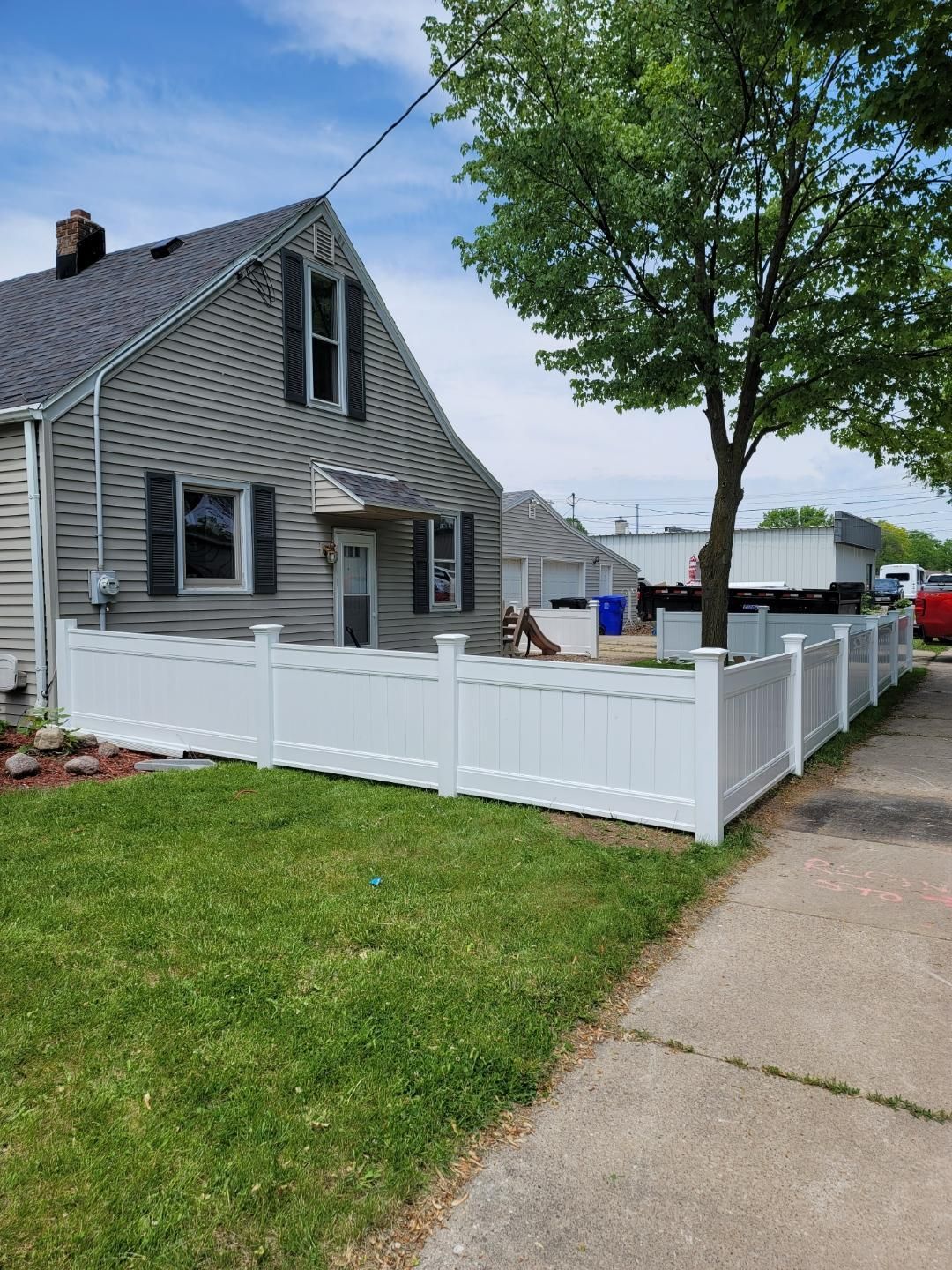 There is a white fence in front of a house.
