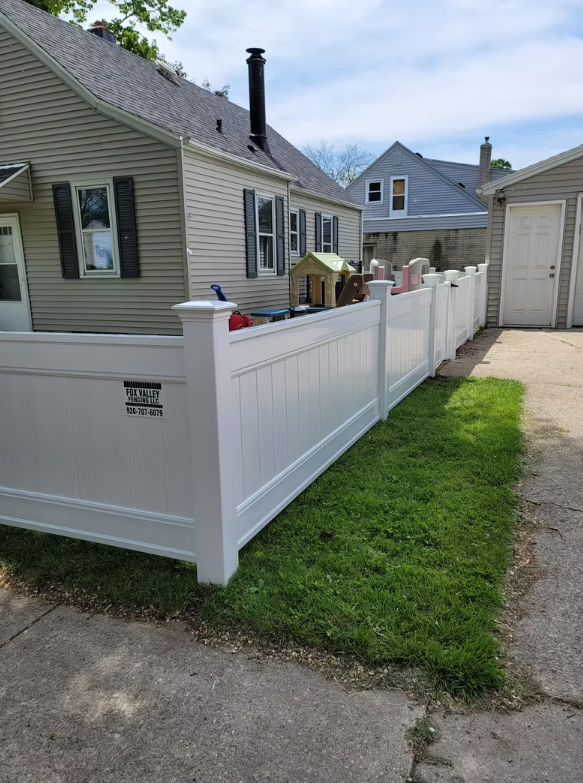 There is a white fence in front of a house.