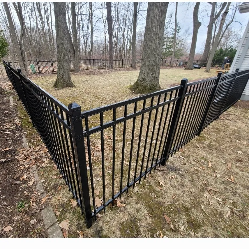 A chain link fence surrounds a lush green field.