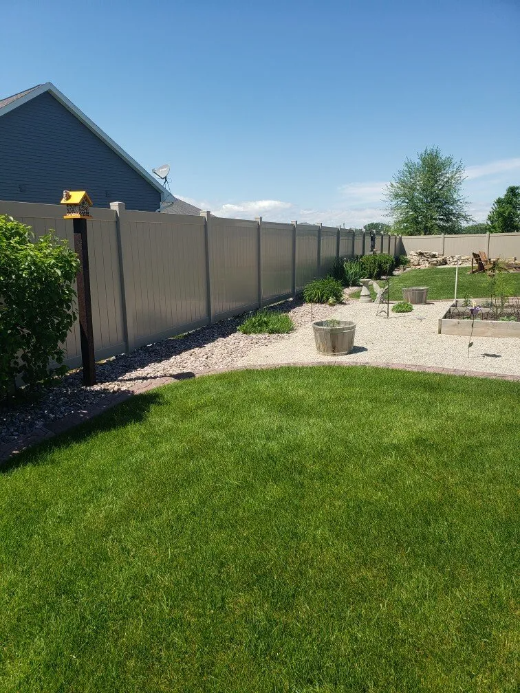 A backyard with a fence and a lush green lawn.