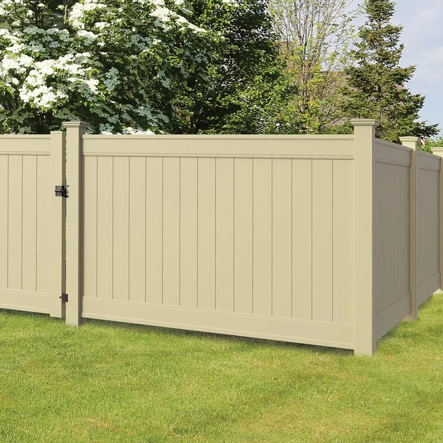 A tan vinyl fence with a gate is sitting on top of a lush green lawn.