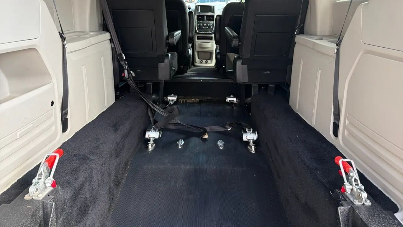 Interior of a white van with black floor mats and seats, viewed from the rear cargo area.
