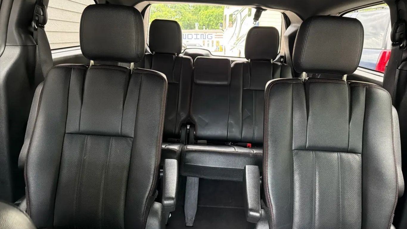 Interior of a vehicle with black leather seats, viewed from the back toward the front rows