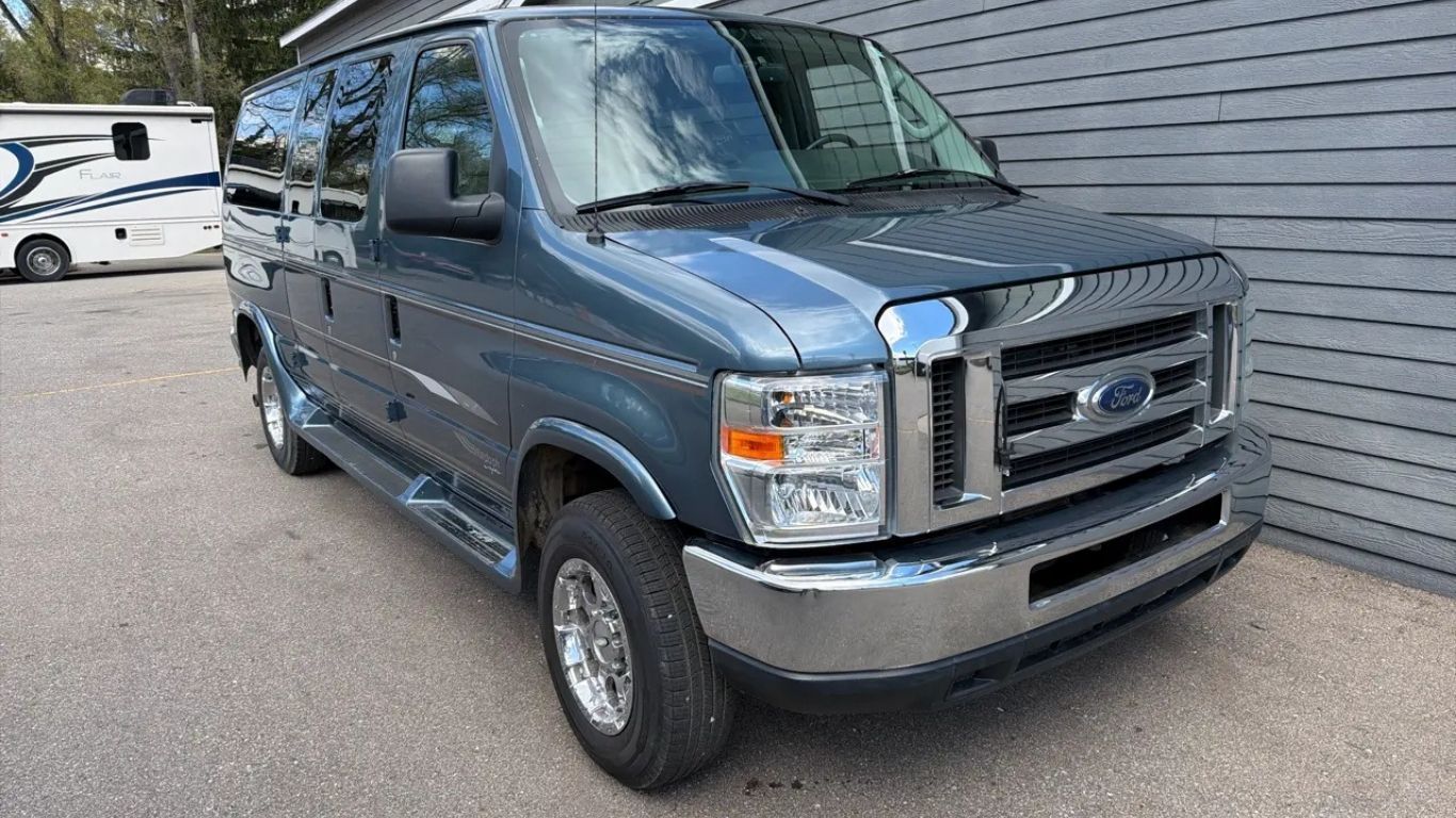 Blue Ford van parked outdoors beside a building, front angled toward the camera.