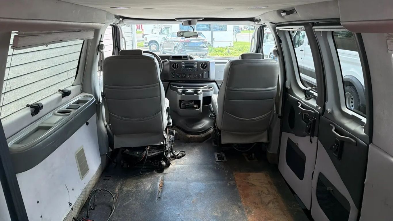Interior of a white van with two front seats, cargo space, and open rear windows.