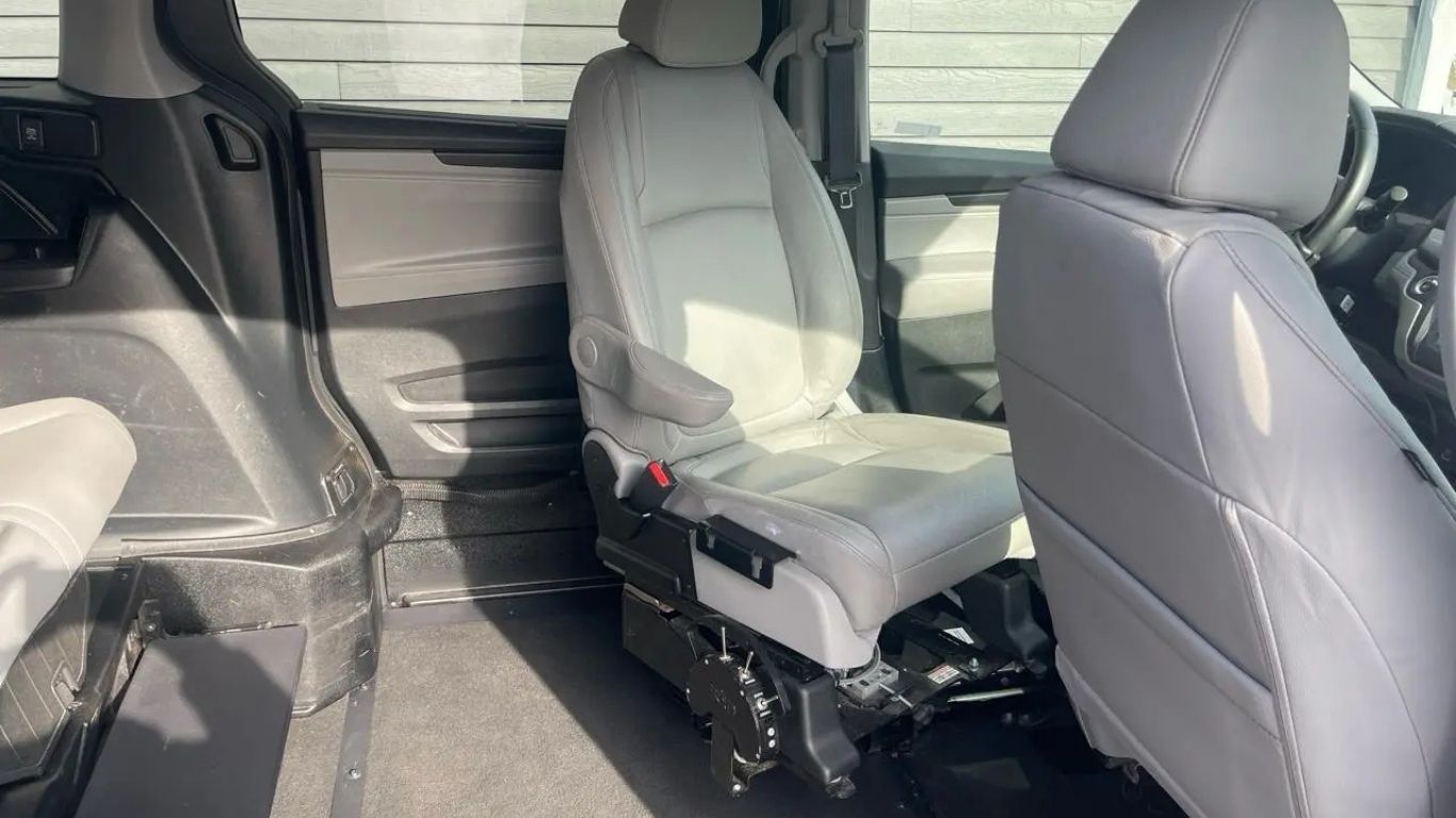 Rear interior of a vehicle with two gray front seats and a plastic-covered middle row seat.