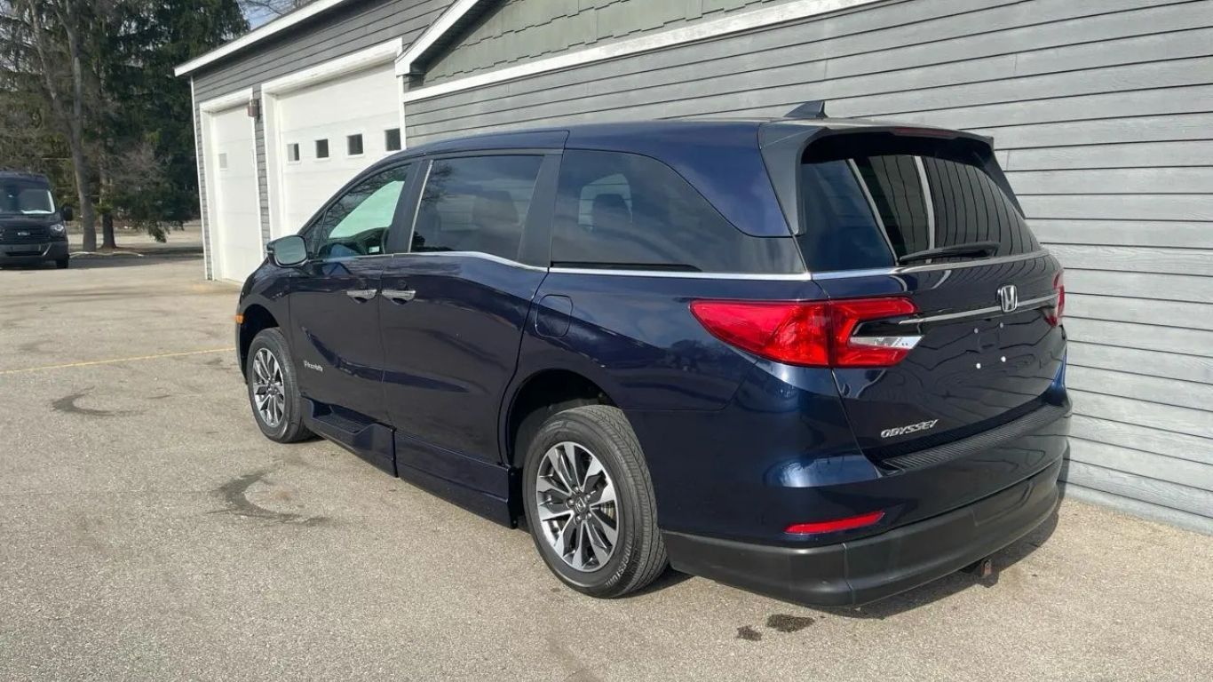 Dark blue minivan parked beside a white garage on a paved driveway