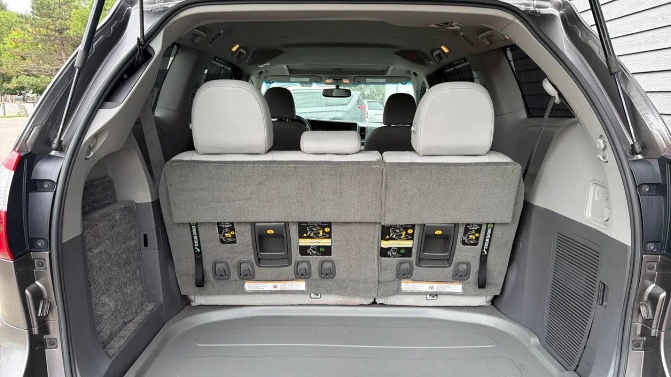 SUV cargo area with third-row seats folded upright, showing rear interior storage space